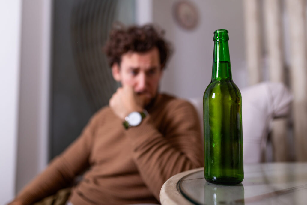 a person looks nervously at a bottle of beer after learning about the alcohol detox timeline