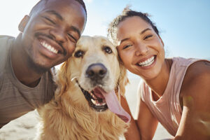 two people and a dog smile on a beach near a costa mesa rehab