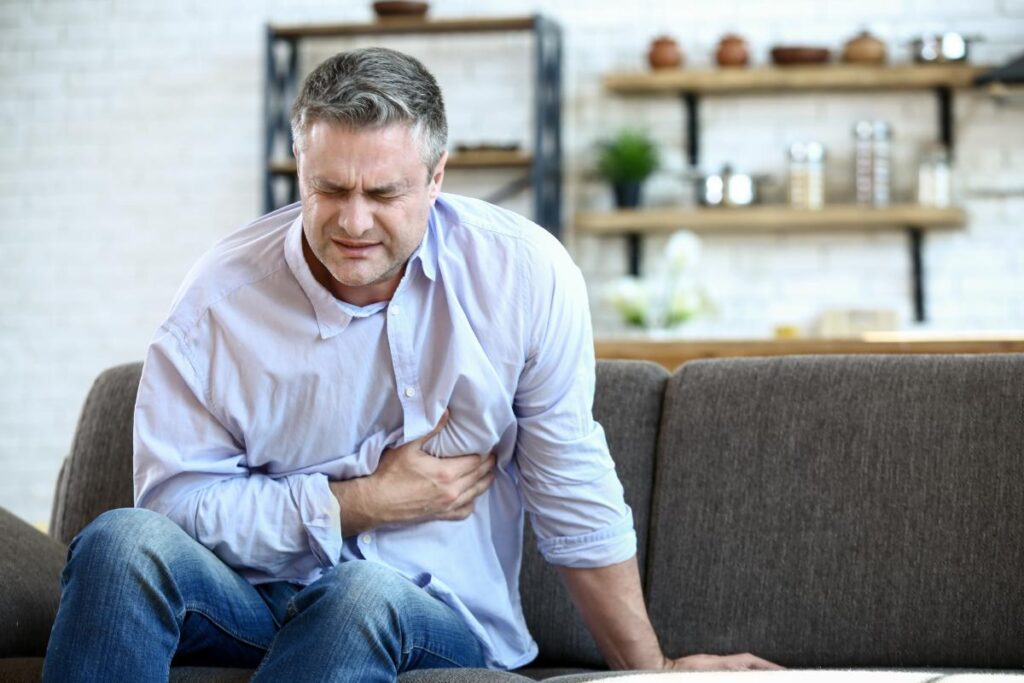 a person on a couch clutches their chest possibly experiencing how cocaine can impact your heart