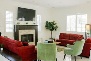 a modern living room with chairs and couches looking toward a television above a fireplace