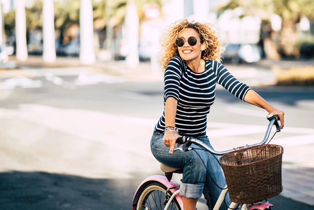 a person smiles as they bike outside, exercise is idea of how to stay sober